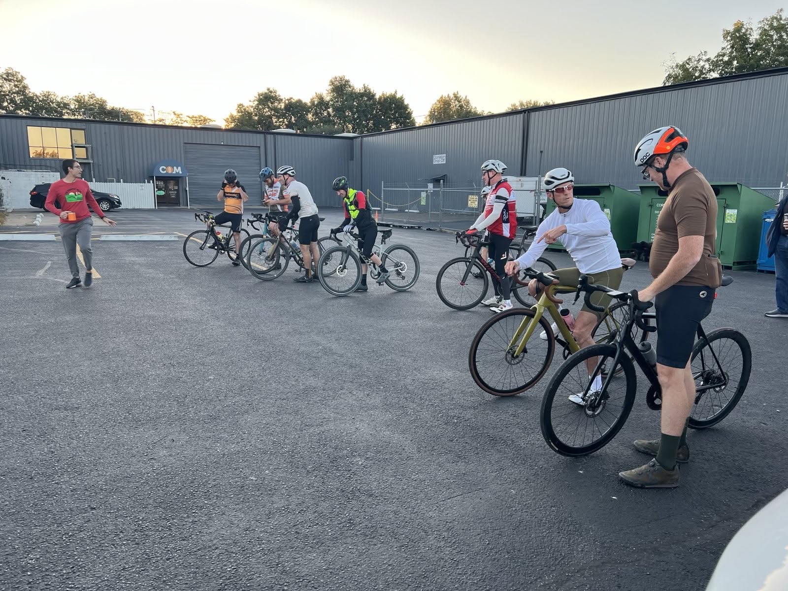 Cyclists gathering and preparing bikes in a parking lot before a community ride